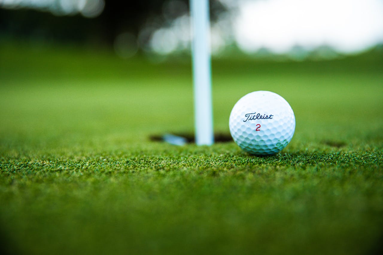 Close-up of a golf ball resting near the hole on a putting green, with the flagstick in view