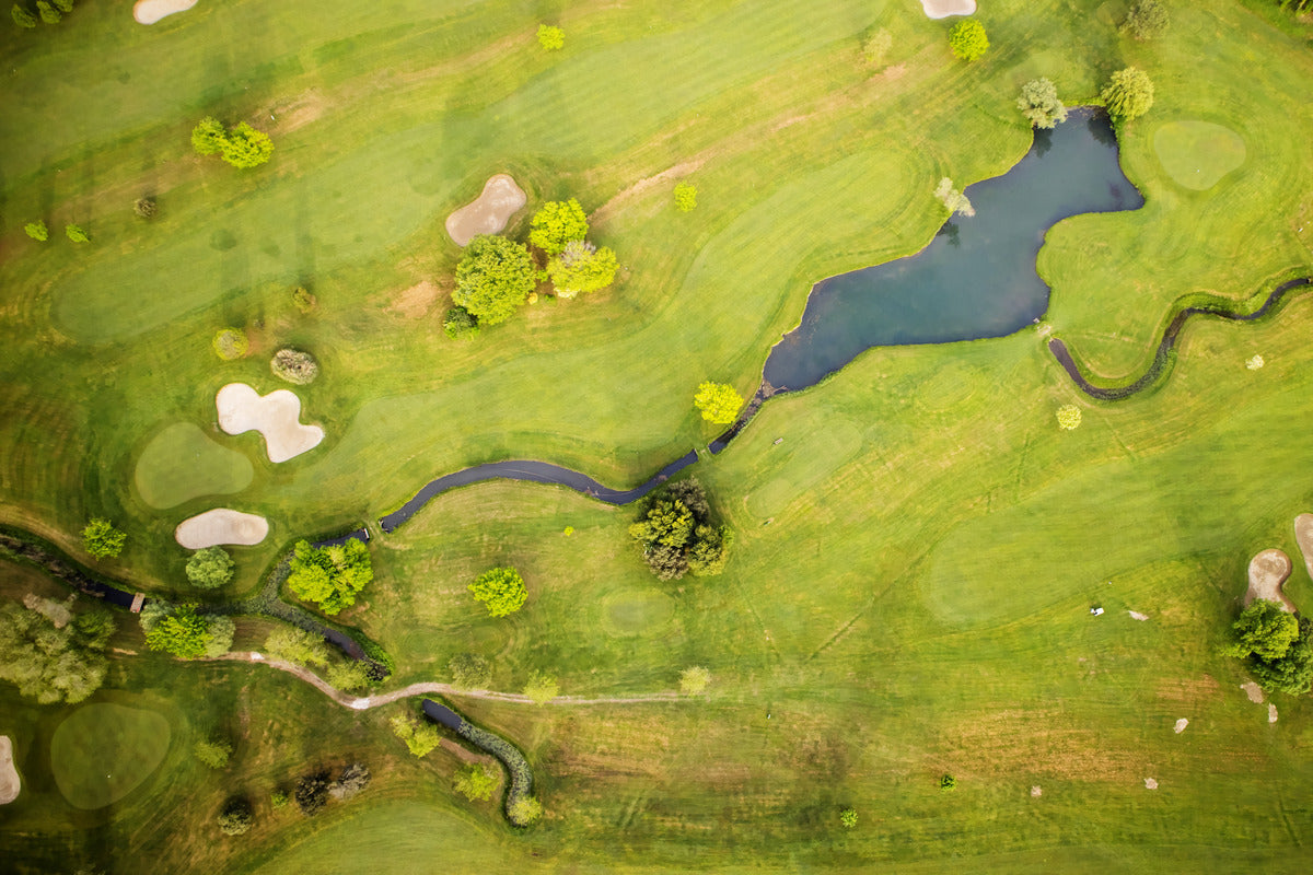 Aerial view of a sprawling golf course landscape, featuring winding greens, sand traps, and water hazards.