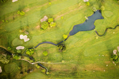 Aerial view of a sprawling golf course landscape, featuring winding greens, sand traps, and water hazards.