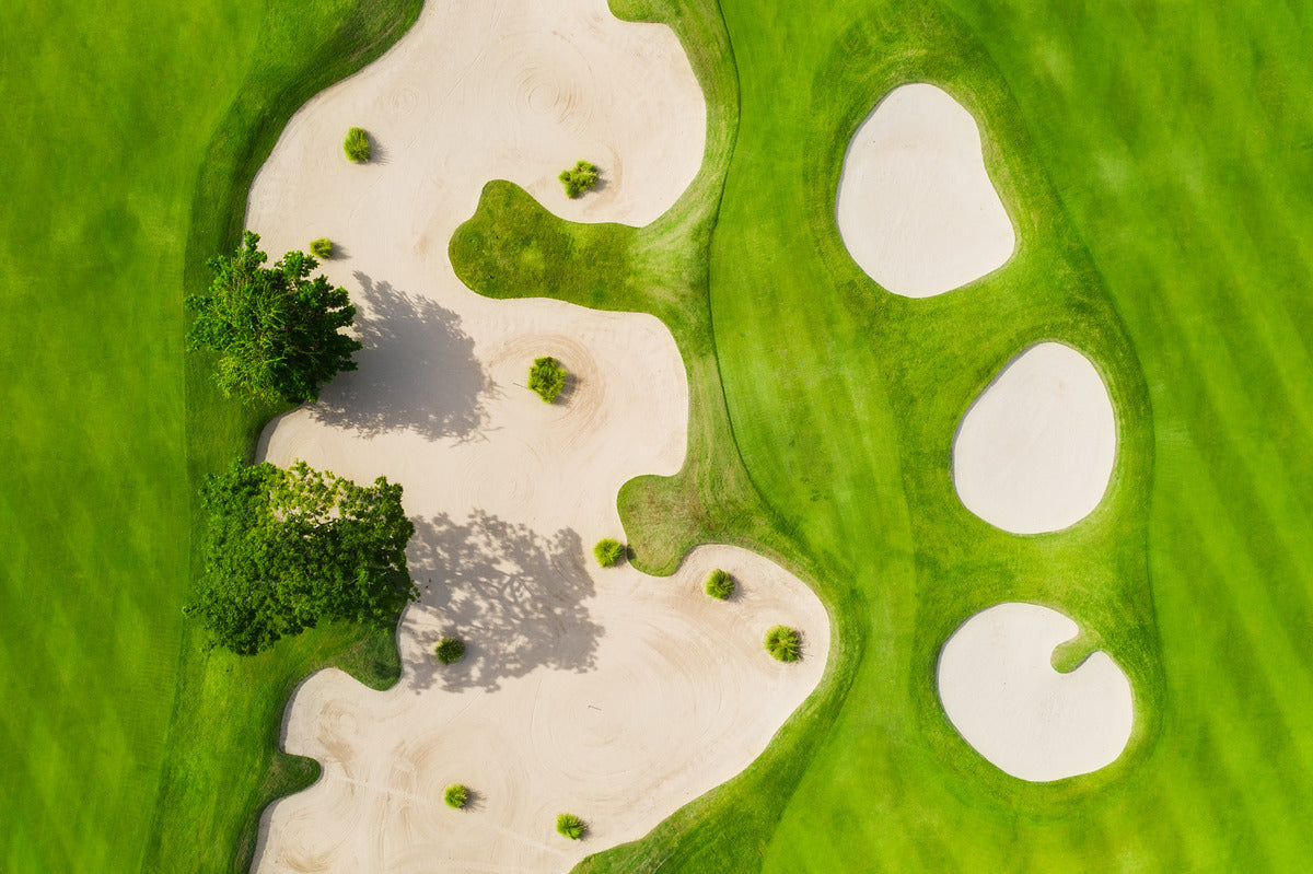 Aerial view of a lush golf course with multiple bunkers and a water hazard, offering a picturesque golf setting.