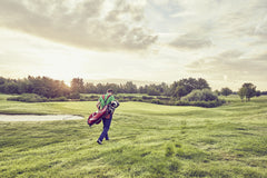 A golfer walking towards the tee box on a professional golf course, preparing for the first shot of the day.
