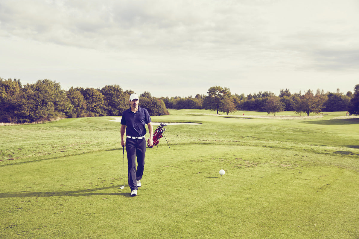A golfer walking along the green fairway, carrying a bag of clubs, experiencing a peaceful golf session.