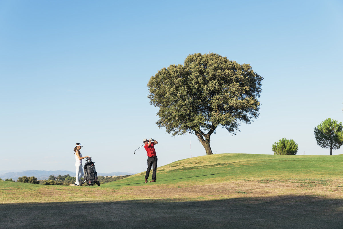 A golfer accompanied by a caddie walking along the course, preparing for a strategic golf day.