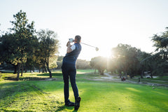 A golfer making a powerful tee-off shot on a bright golf course, capturing the energy of the game.