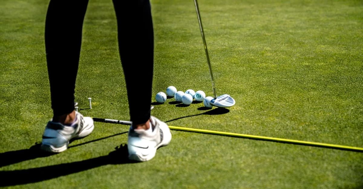 A golfer crouching to study the line of a putt on a manicured putting green