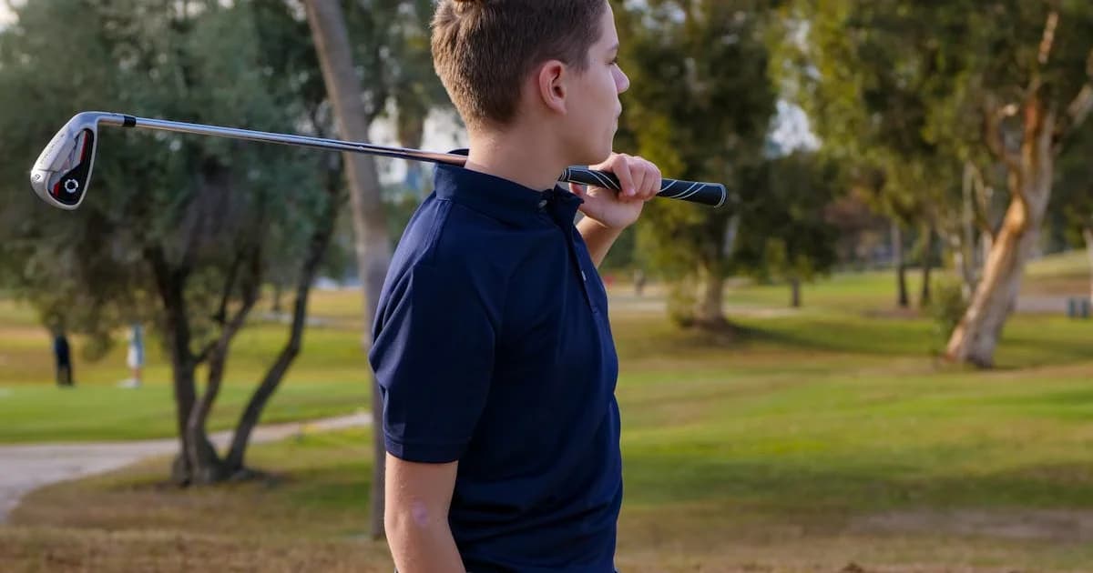 A teenage boy hitting a golf shot on a well-kept fairway on a bright day