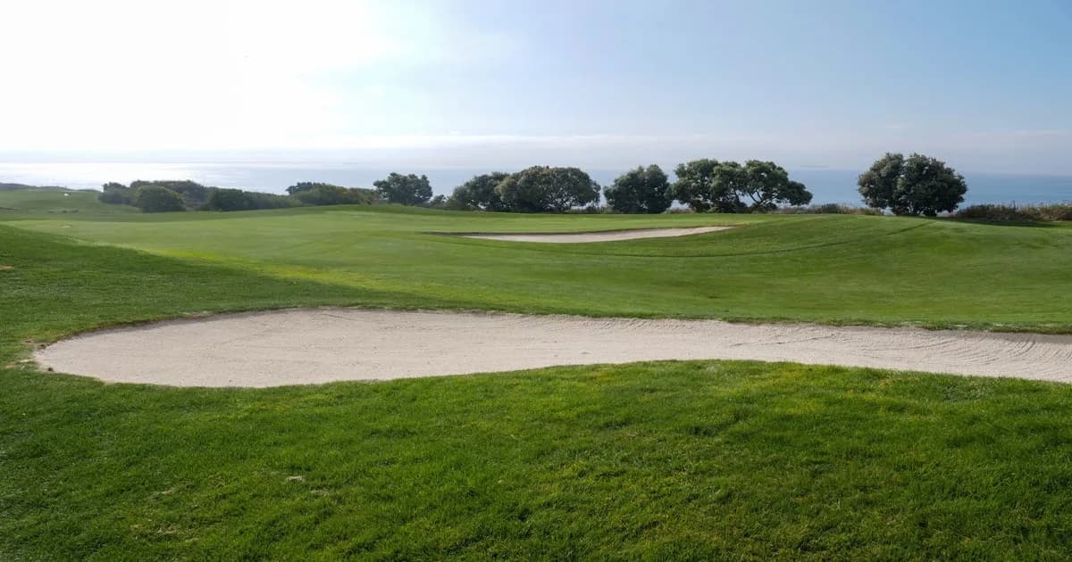 An aerial view of a beautifully manicured golf course with bunkers and greens