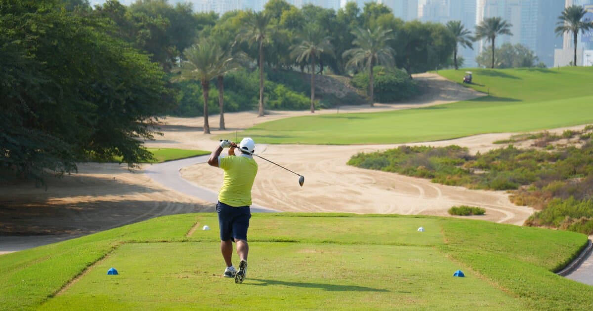 A golfer completing a driver swing with the fairway laid out ahead