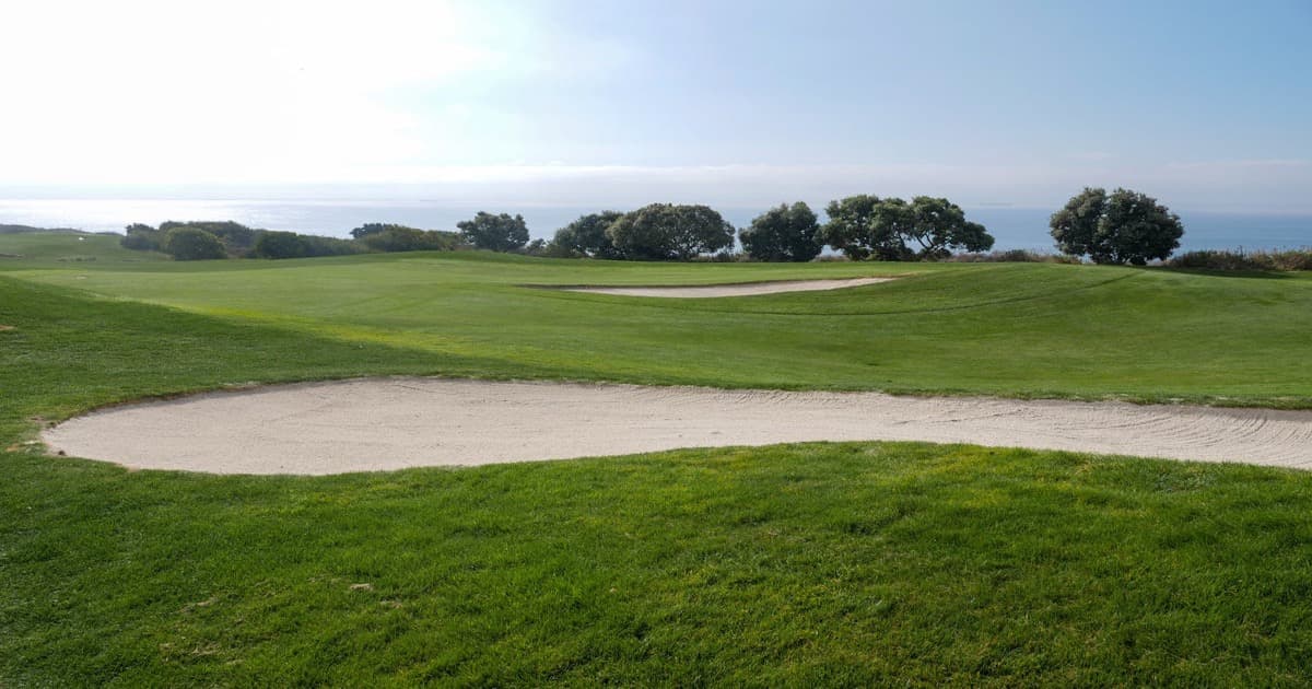 An aerial view of a beautifully manicured golf course with bunkers and greens