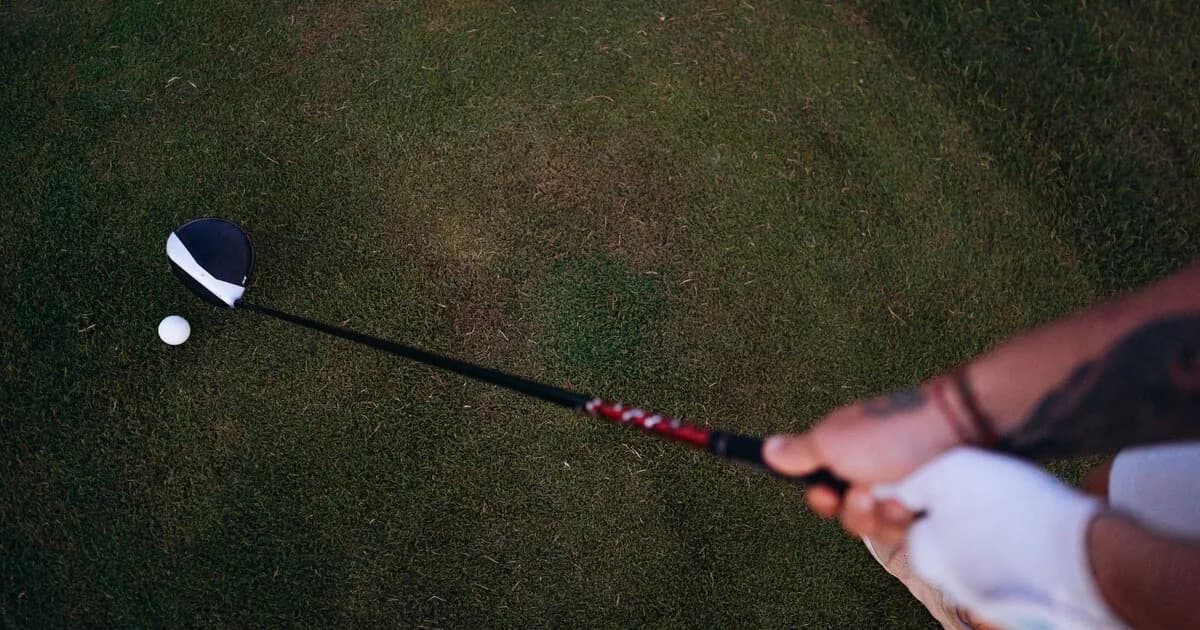 Overhead view of a golfer's hands on the grip with the clubhead behind the ball at address