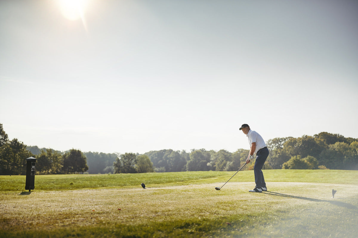 A senior golfer preparing to tee off, participating in a premium golf experience package.