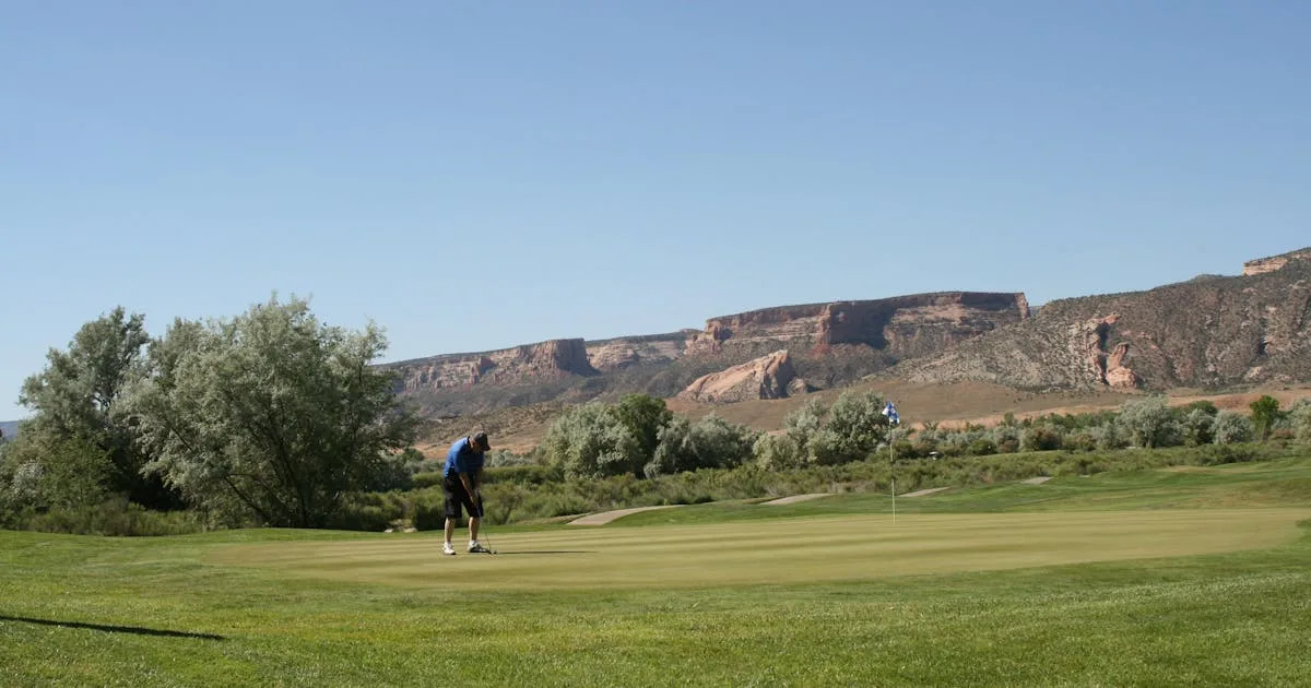 A dramatic view down a golf fairway lined with trees on a clear afternoon