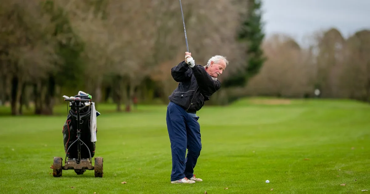A golfer walking along a scenic coastal golf course in warm light