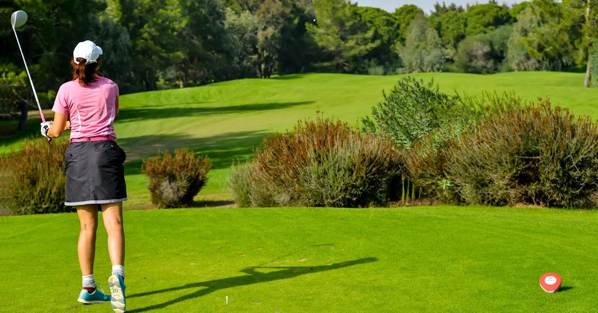A woman golfer smiling on a green course with rolling hills in the background
