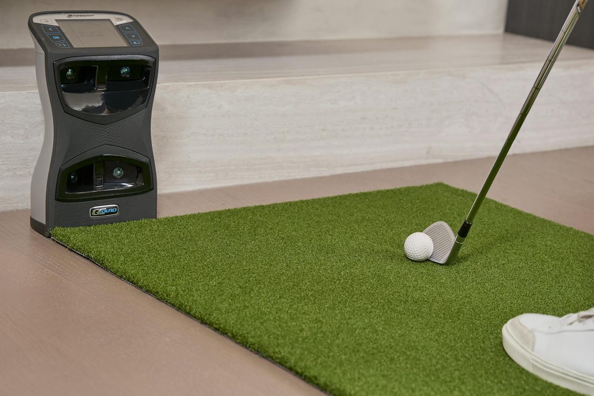 A golfer playing an indoor golf simulator with a large screen showing a virtual course