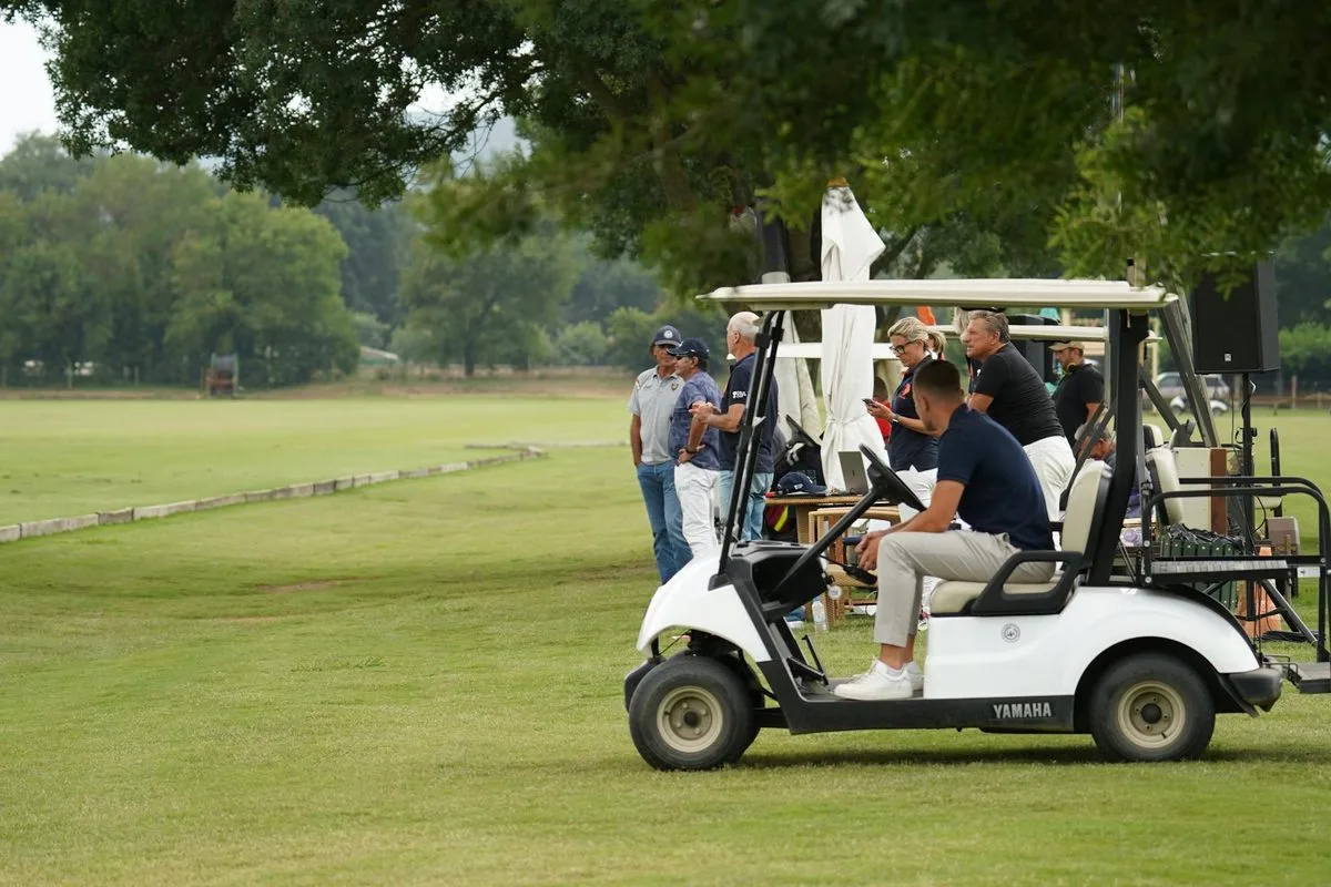 A group of men celebrating on a golf course with clubs in hand on a summer day
