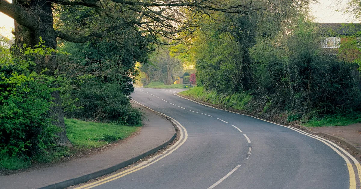 Winding country road through lush green English countryside in spring