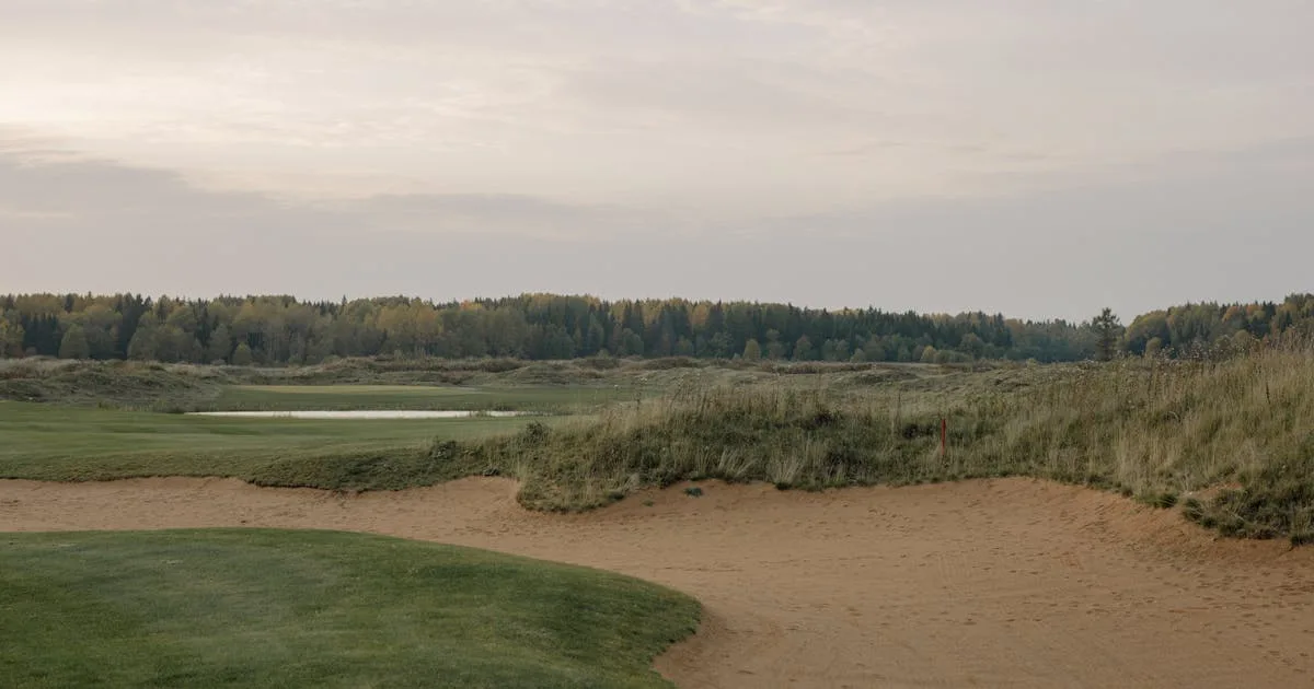 A peaceful golf course landscape at dawn with sand trap and distant trees