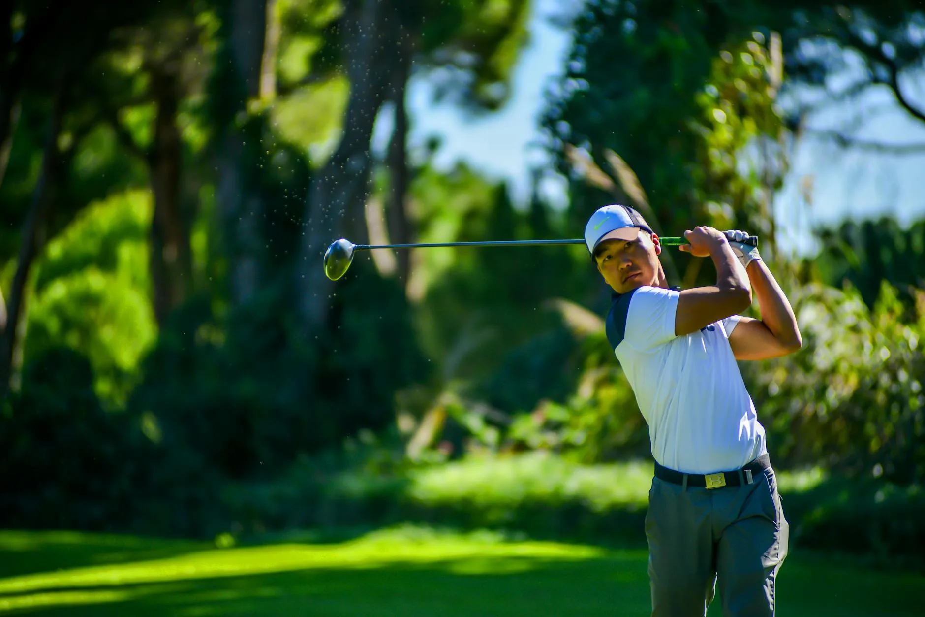 A golfer at the top of their backswing on a sunny fairway