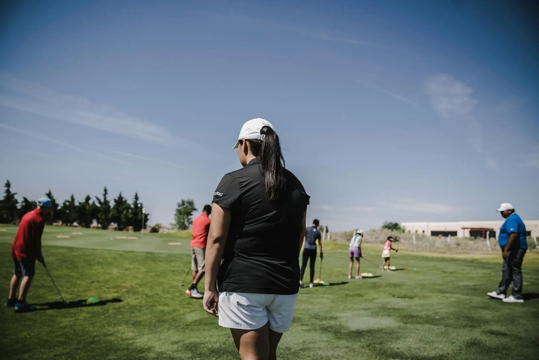 Two golfers walking along a fairway on a sunny day carrying their bags